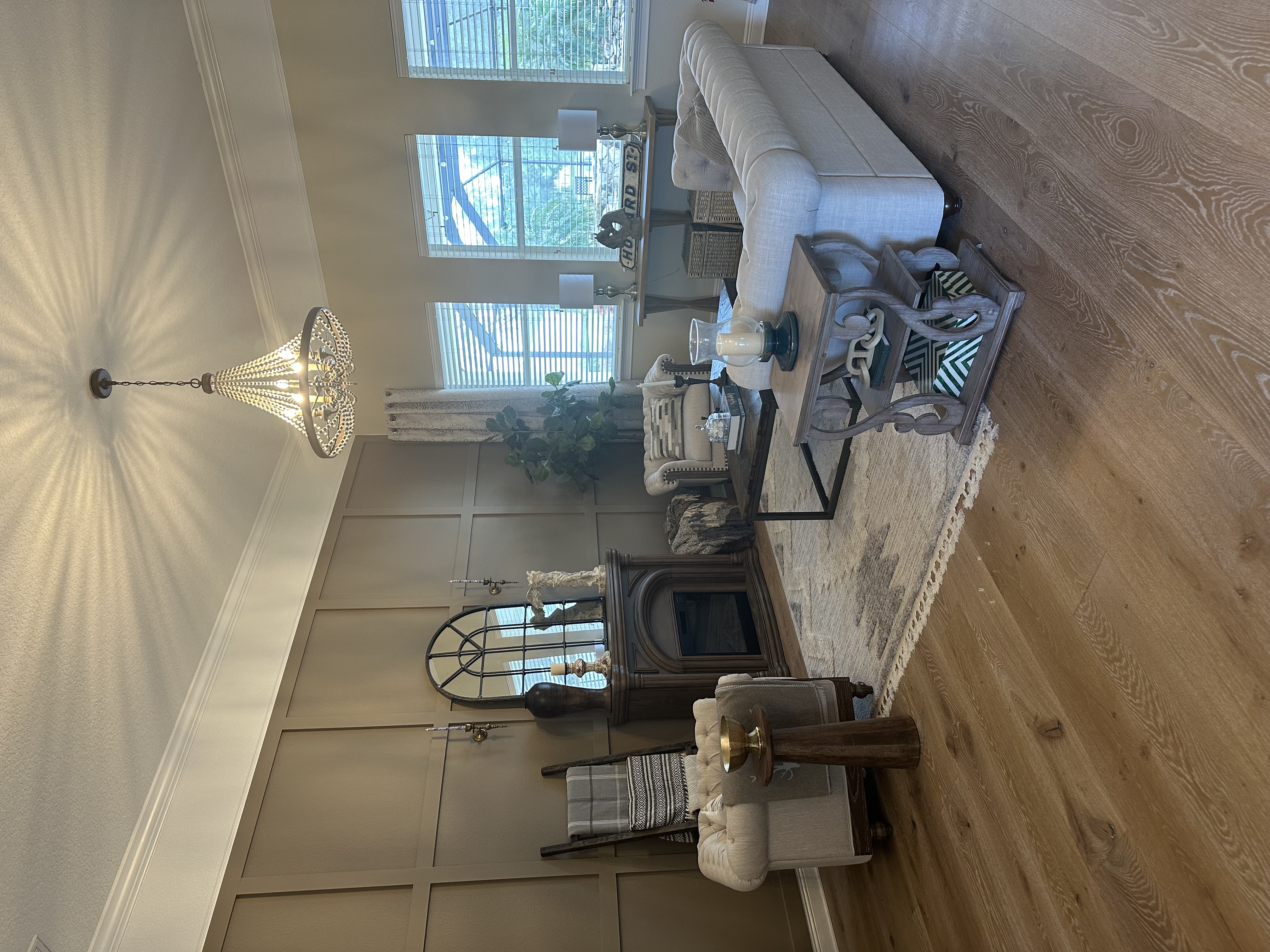 Living room with taupe board-and-batten accent wall, tufted Chesterfield sofa, arched mirror over fireplace — Lithia, FL