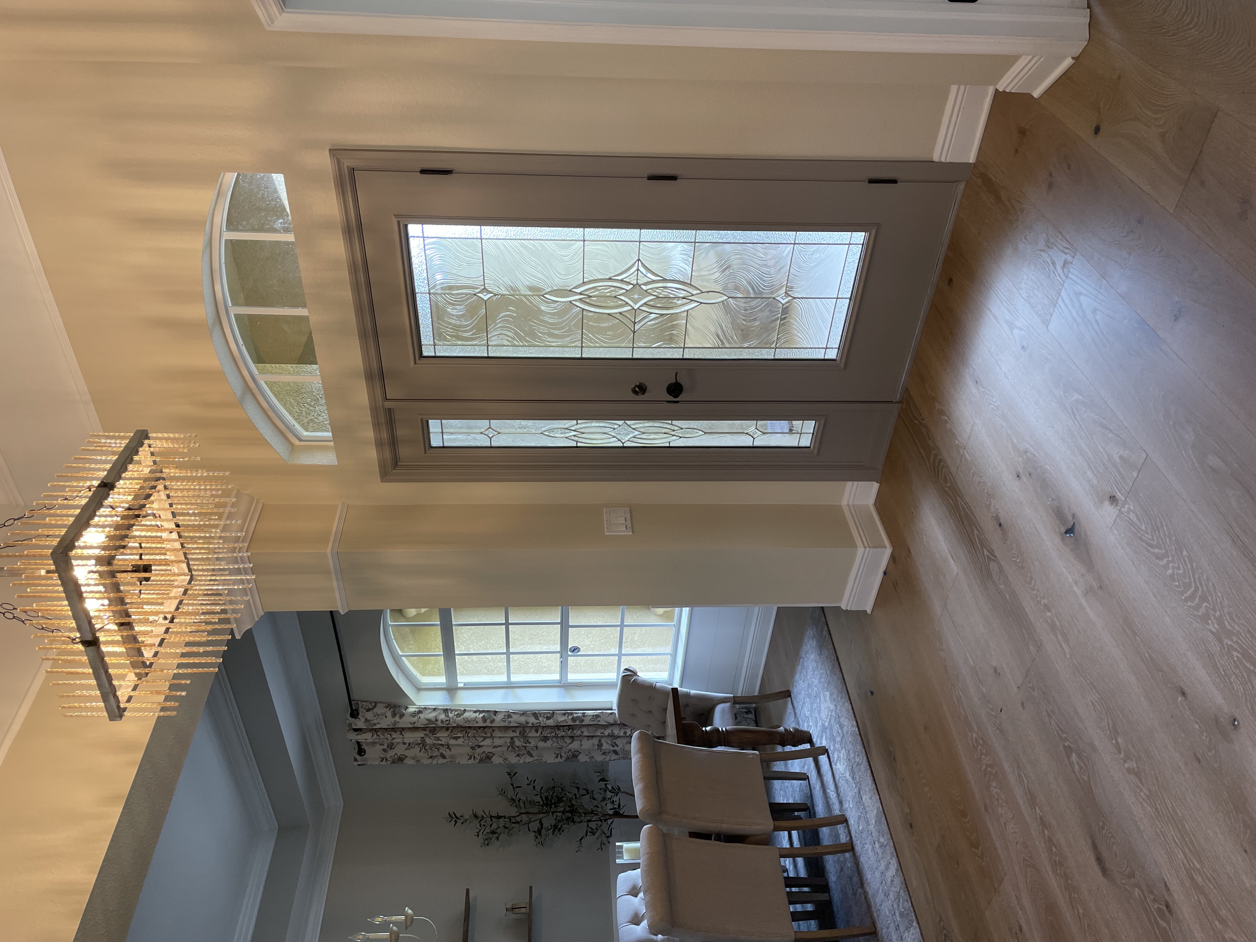 Grand entry foyer with crystal chandelier, arched transom door with decorative glass, and wide-plank hardwood floors — Lithia, FL
