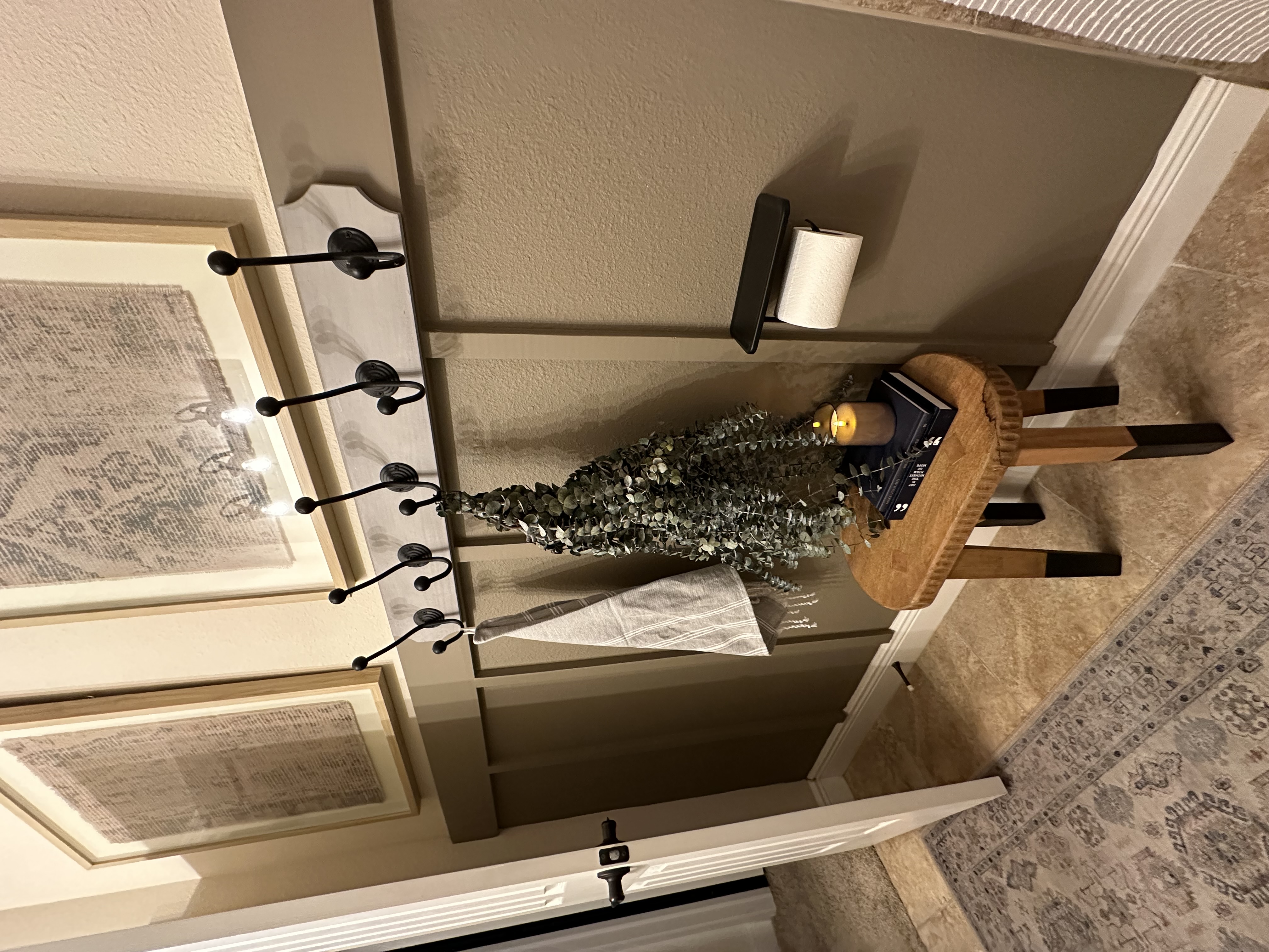 Hallway styling detail with board-and-batten wall, iron hook rail, dried eucalyptus, and stacked books — Lithia, FL